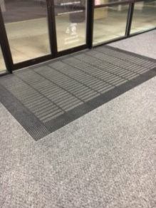 Black entry mat by glass doors.