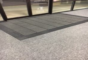 Carpeted entry mat just inside of glass doors.